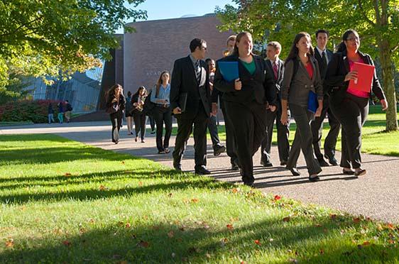 A group of students dressed in business attire walk along a stone path at 麻豆影音.