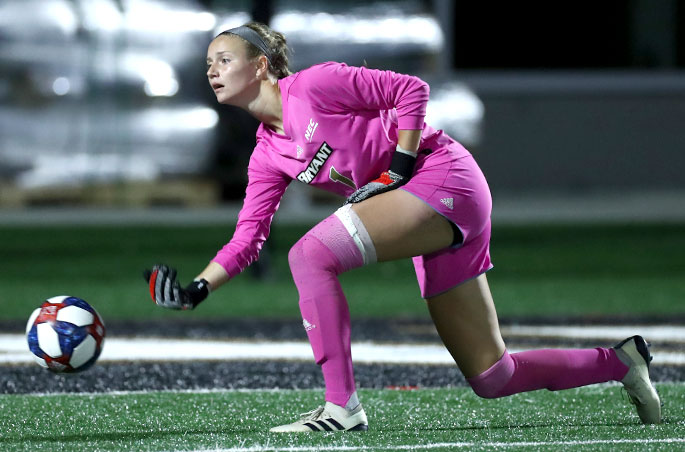 A goalie for the Bryant women's soccer team rolls out the ball during a home game.
