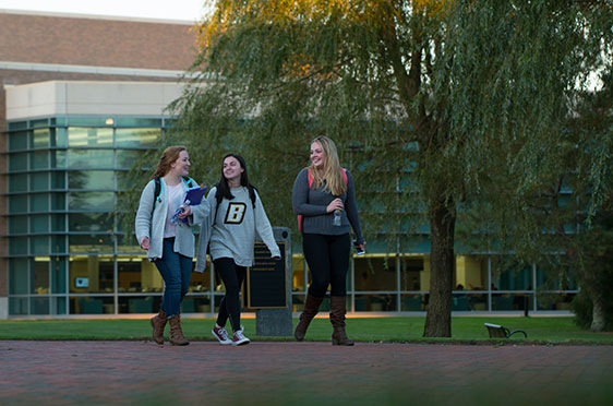 A group of three female students walk along a brick pathway in front of the George E. Bello Center for Information and Technology at 鶹Ӱ.