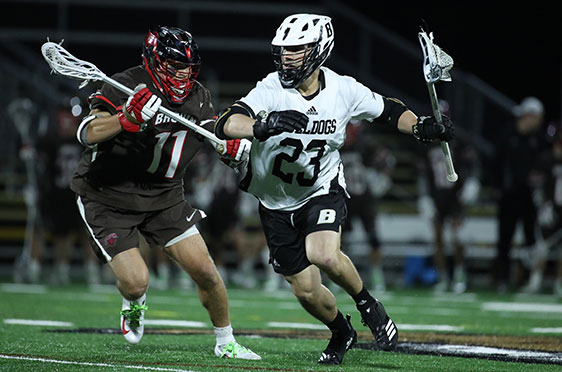 A 鶹Ӱ men's lacrosse player runs past a Brown University during a game at Beirne Stadium.
